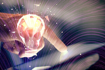 Double exposure of man's hands holding and using a digital device and bulb hologram drawing. Idea concept.