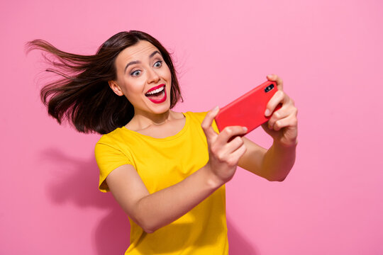 Portrait of attractive trendy cheerful girl playing gadget web app having fun isolated over pink pastel color background
