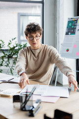 Young businessman working with documents near calculator in office.