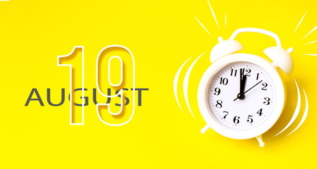 August 19th. Day 19 of month, Calendar date. White alarm clock with calendar day on yellow background. Minimalistic concept of time, deadline. Summer month, day of the year concept.