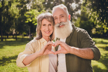 Photo of retired pensioner husband wife grey haired old couple make fingers heart shape summer...