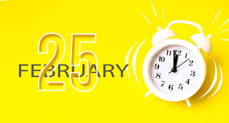 February 25th. Day 25 of month, Calendar date. White alarm clock with calendar day on yellow...