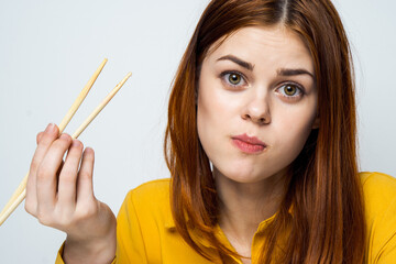 woman eating sushi with japanese chopsticks posing light background