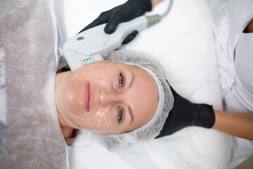 Obraz na płótnie Canvas A woman in a cosmetology office receives a SMAS lifting procedure. Non-surgical ultrasound facelift, rejuvenation, moisturizing, getting rid of wrinkles, skin tone and elasticity
