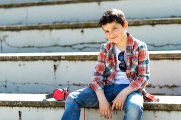 Cheerful caucasian boy sitting on bleachers at city park while looking at camera