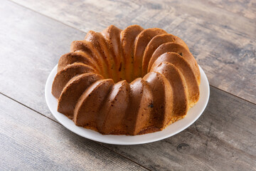 Traditional bundt cake piece with raisins on wooden table	