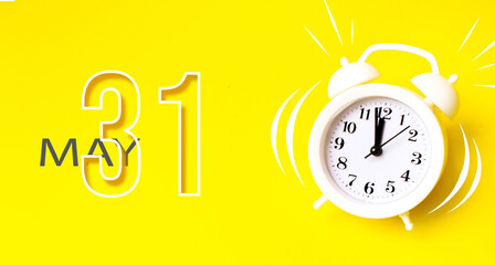 May 31st . Day 31 of month, Calendar date. White alarm clock with calendar day on yellow background. Minimalistic concept of time, deadline. Spring month, day of the year concept.