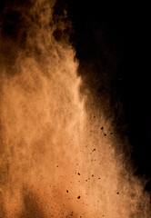 flying brown cocoa particles on a black background. Powder flies up