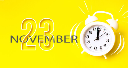 November 23rd. Day 23 of month, Calendar date. White alarm clock with calendar day on yellow...