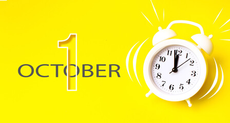 October 1st . Day 1 of month, Calendar date. White alarm clock with calendar day on yellow...