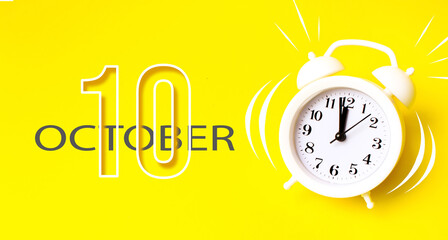 October 10th. Day 10 of month, Calendar date. White alarm clock with calendar day on yellow...
