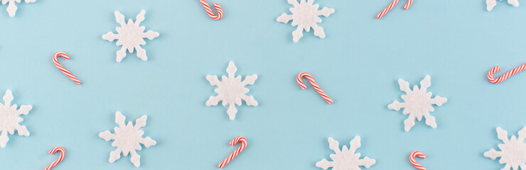 Christmas composition. Banner made of snowflakes, red and white candies on blue background. Christmas, winter, new year concept. Minimal style. Flat lay, top view