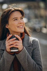 Young woman walking in the street and drinking coffee
