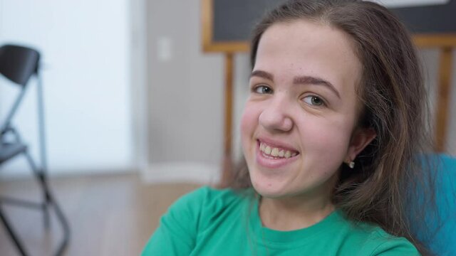 Headshot portrait shy Caucasian little person smiling looking at camera. Close-up happy smiling face of young woman posing indoors. Genetic mutation and confidence concept
