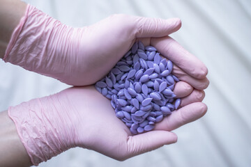 Depilation master holds purple hair removal wax in pink gloves