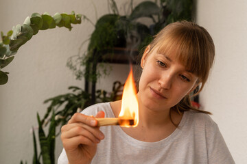 Young female looking how aroma wooden stick burning. Aromatherapy incense practice