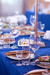 Elegant table setting white plates with napkins on blue tablecloth, tableware served empty table in a restaurant, Empty glasses, luxury tableware concept