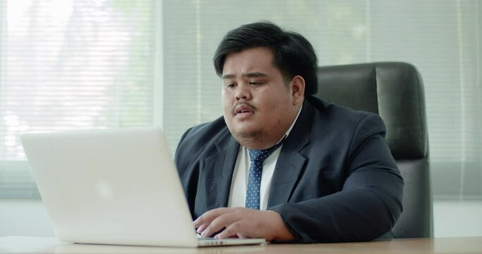 Asian business man which has a fat figure and funny personality, wearing a suit like an executive or a manager using a laptop in the office. Later, he had a business failure that made him sad.