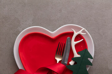 Festive Christmas meal background. Heart shaped plate with knife and fork and Christmas antler and...