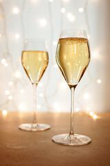 Two flute glasses of champagne or sparkling wine in a Christmas or New Year atmosphere, bokeh lights in the background