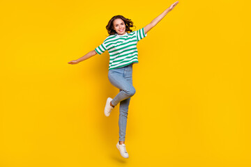 Fototapeta na wymiar Full body photo of young cheerful girl have fun jump up fly active hands wings isolated over yellow color background