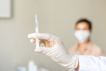 Anonymous healthcare worker vaccinating middle-aged female patient. Blurred background