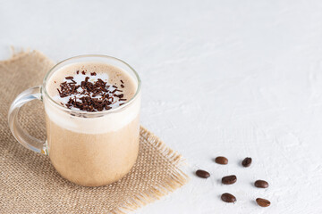 Vegan mochaccino coffee with nuts and chocolate in a glass cup.