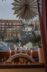 Obraz na płótnie Canvas New Year's decoration on the windowsill, a vase with fir branches on the background of the city outside the window.
