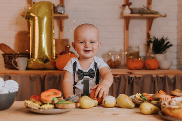 smiling one-year-old baby boy in festive clothes holds an apple in his hands. first birthday. body with the number one. golden foil ball. healthy snack for kids. little chef. High quality photo