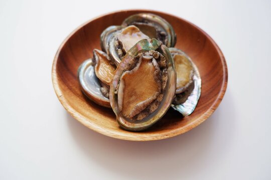 Raw abalone on the white background. Abalones on wooden dish. Fresh Sea food, Cooking ingredients.