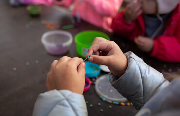little children's hands weave a bead bracelet close-up shot