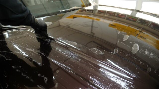 Close up to PPF installation process on a front headlight and hood. PPF is a Paint Protection Film which protect paint from scratches and stone chips. Concept of: Guard, Protect, Car, New, Work.	

