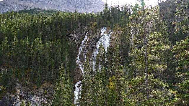 View of water fall on Grassi Lakes Trail near Canmore, Alberta, Kanada in Kananaskis Country in the Rocky Mountains in autumn season with rocks, forest and power line.