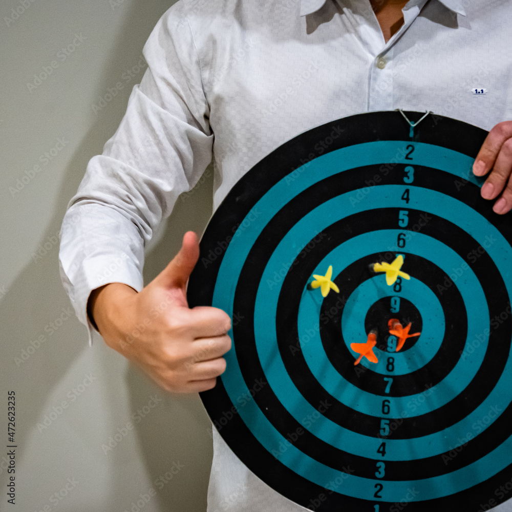 Poster close up shot of the dart arrow hit on bulleyes of dartboard to represent that the business reached 