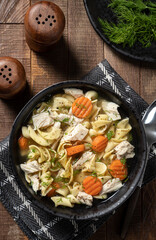 Bowl of chicken noodle soup on a wooden table - 472623202