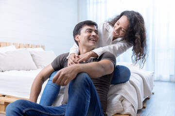 Happy young couple hugging and laughing in bedroom.