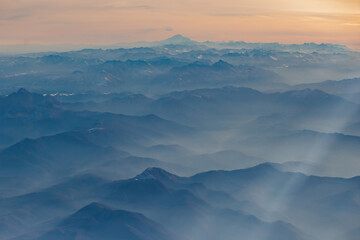 View from the plane to the North Caucasus, in the distance Elbrus. High mountains in the morning haze