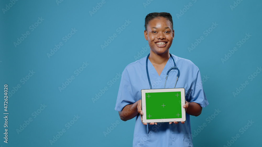 Poster medical assistant showing tablet with horizontal green screen at camera. nurse with uniform and stet