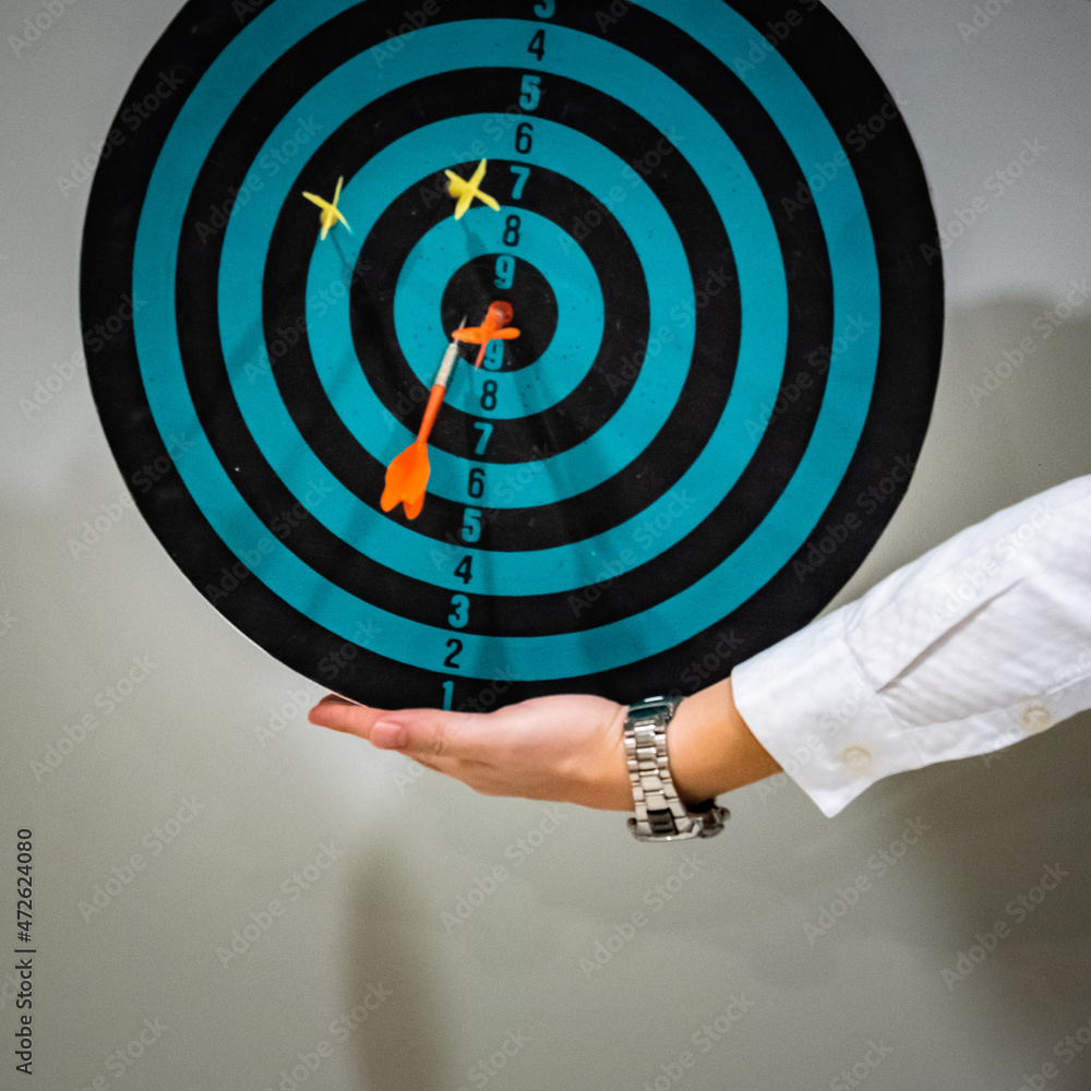 Poster close up shot of the dart arrow hit on bulleyes of dartboard to represent that the business reached 