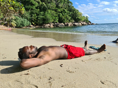 A young man lying on the beach in Seychelles 