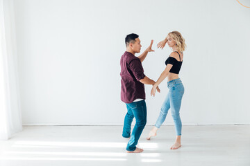 a man and a woman dance to the music of a paired dance of bachata in a white room