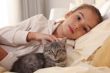 Cute little child with kitten at home, focus on pet
