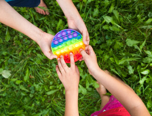Kids' hands holding round pop it toy