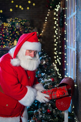 Santa Claus sends a gift by mail. A man dressed as a Santa puts a decorated box in a mailbox