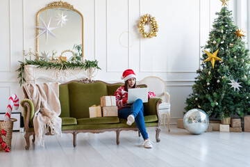 Young woman sitting on couch in a decorated living room working on laptop computer