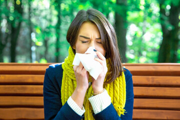 Woman blowing nose outside