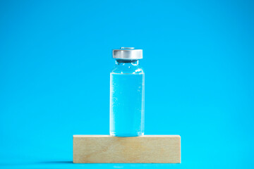Glass vaccine bottle stands on a wooden cube.