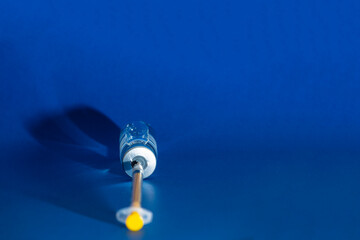 Coronavirus vaccine with syringe inserted on blue background