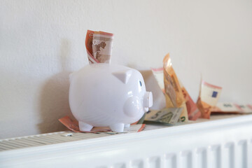 Home heating expenses and savings concept. Piggy bank and money on heating radiator.