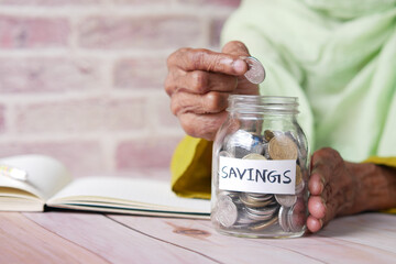 senior women saving coins in a jar white sited